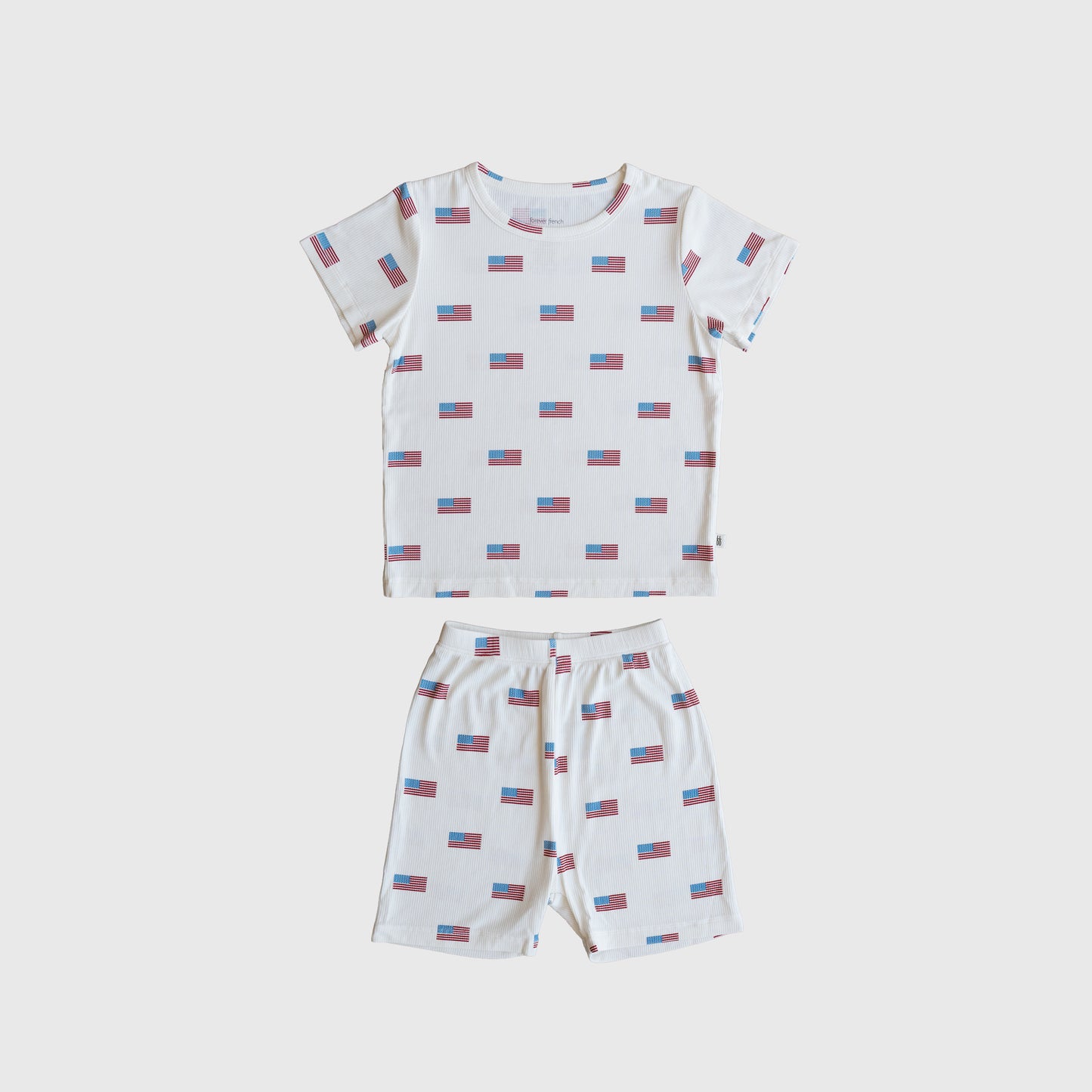 The Bamboo Short Set | Americana Ribbed by forever french baby is a ribbed bamboo short-sleeve pajama set with a white base and red/blue rectangular pattern, including a t-shirt and matching shorts, shown laid flat on white.