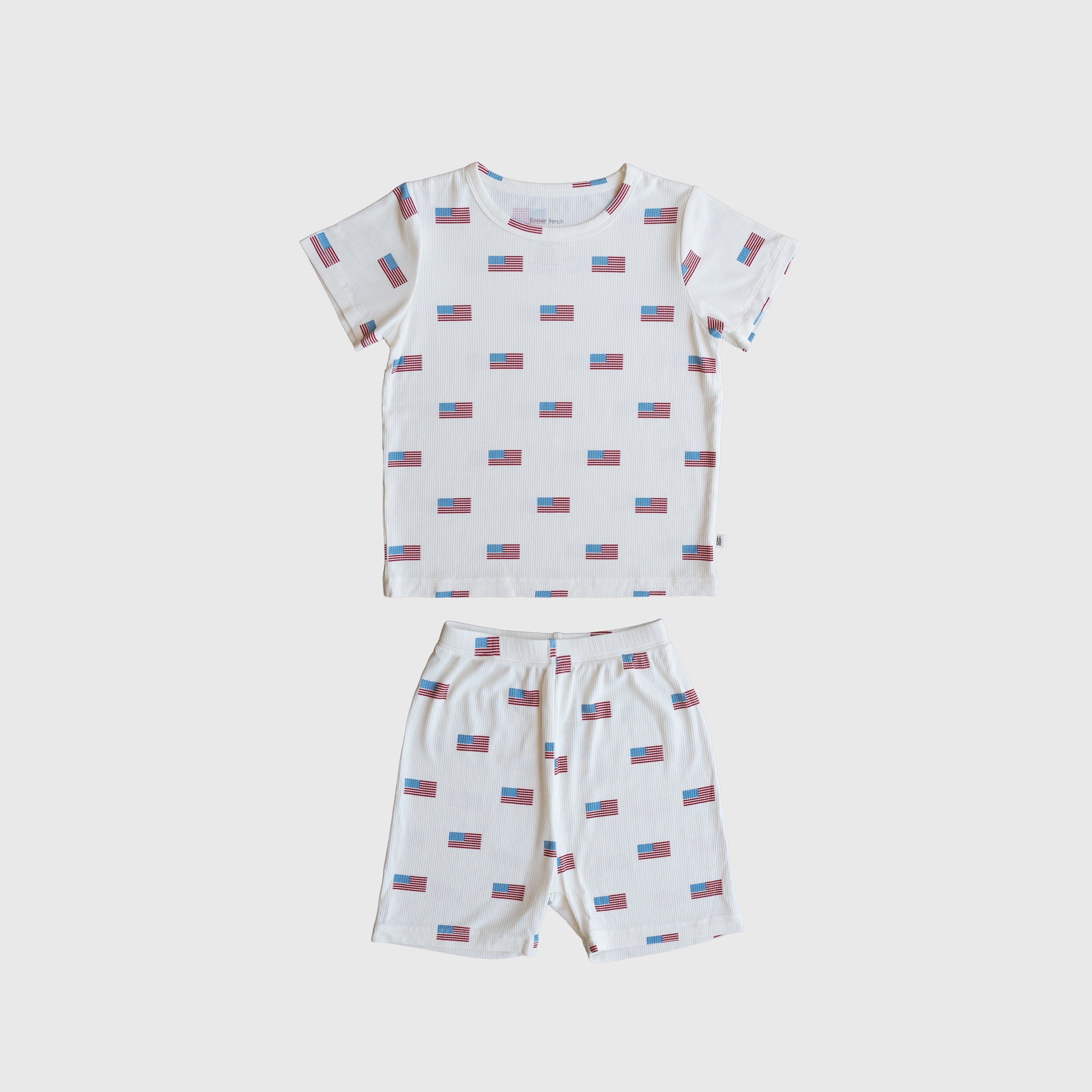 The Bamboo Short Set | Americana Ribbed by forever french baby is a ribbed bamboo short-sleeve pajama set with a white base and red/blue rectangular pattern, including a t-shirt and matching shorts, shown laid flat on white.