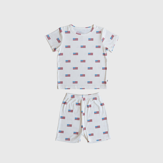 The Bamboo Short Set | Americana Ribbed by forever french baby is a ribbed bamboo short-sleeve pajama set with a white base and red/blue rectangular pattern, including a t-shirt and matching shorts, shown laid flat on white.