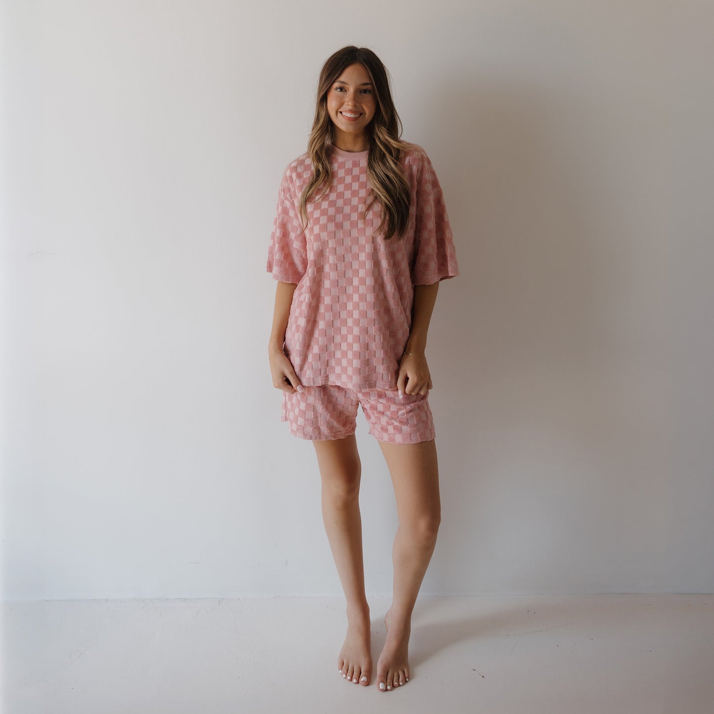 A woman smiles at the camera in the forever french baby Women's Terry Short Set in Sea Pink—an ultra-cozy lounge set perfect for relaxing or creating coordinated family matching outfits.