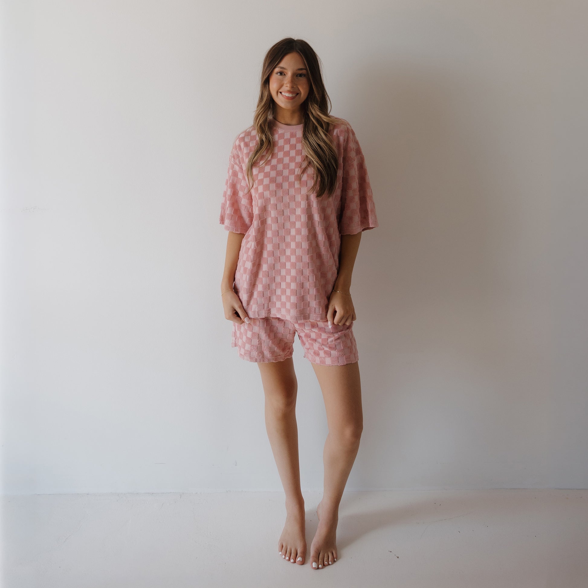 A woman smiles at the camera in the forever french baby Women's Terry Short Set in Sea Pink—an ultra-cozy lounge set perfect for relaxing or creating coordinated family matching outfits.
