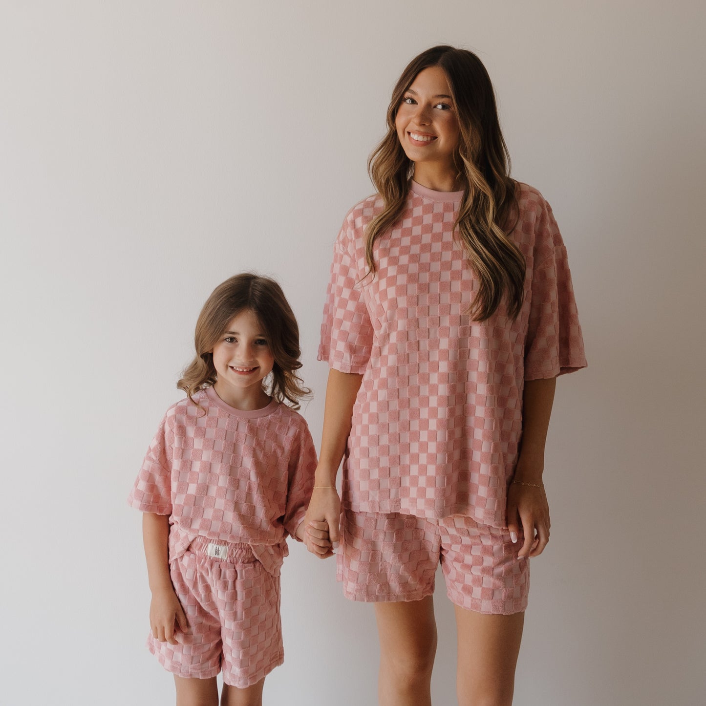 A woman and a young girl smile and hold hands in matching forever french baby Women's Terry Short Set in Sea Pink, standing against a plain white background.