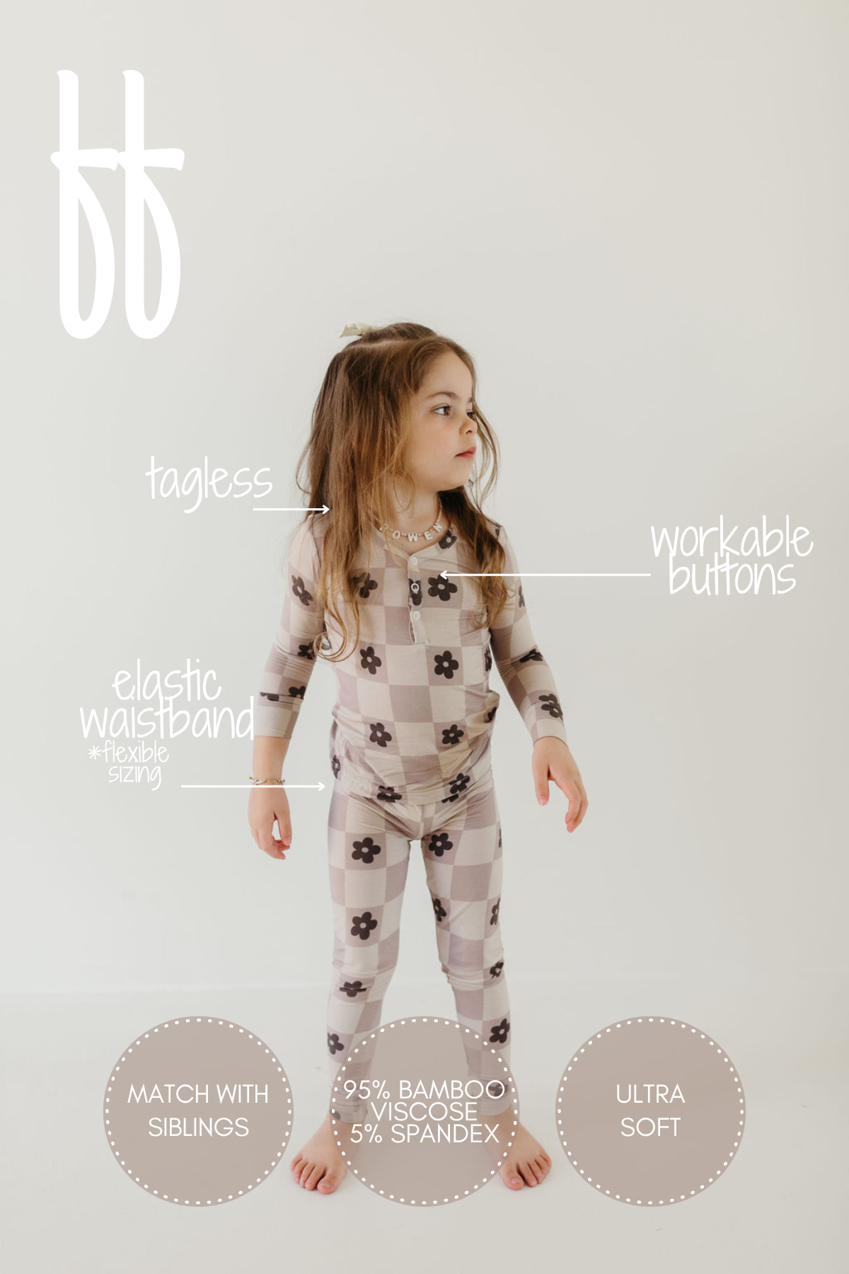 A young child stands barefoot in the "Bamboo Two Piece Pajamas | Flower Child" by forever french baby, showcasing a brown checkered pattern with floral accents. This hypo-allergenic sleepwear is made from a 95% bamboo viscose blend, offering ultra softness and featuring breathable, tagless fabric with workable buttons and an elastic waistband. Plus, there's the potential for sibling matching!