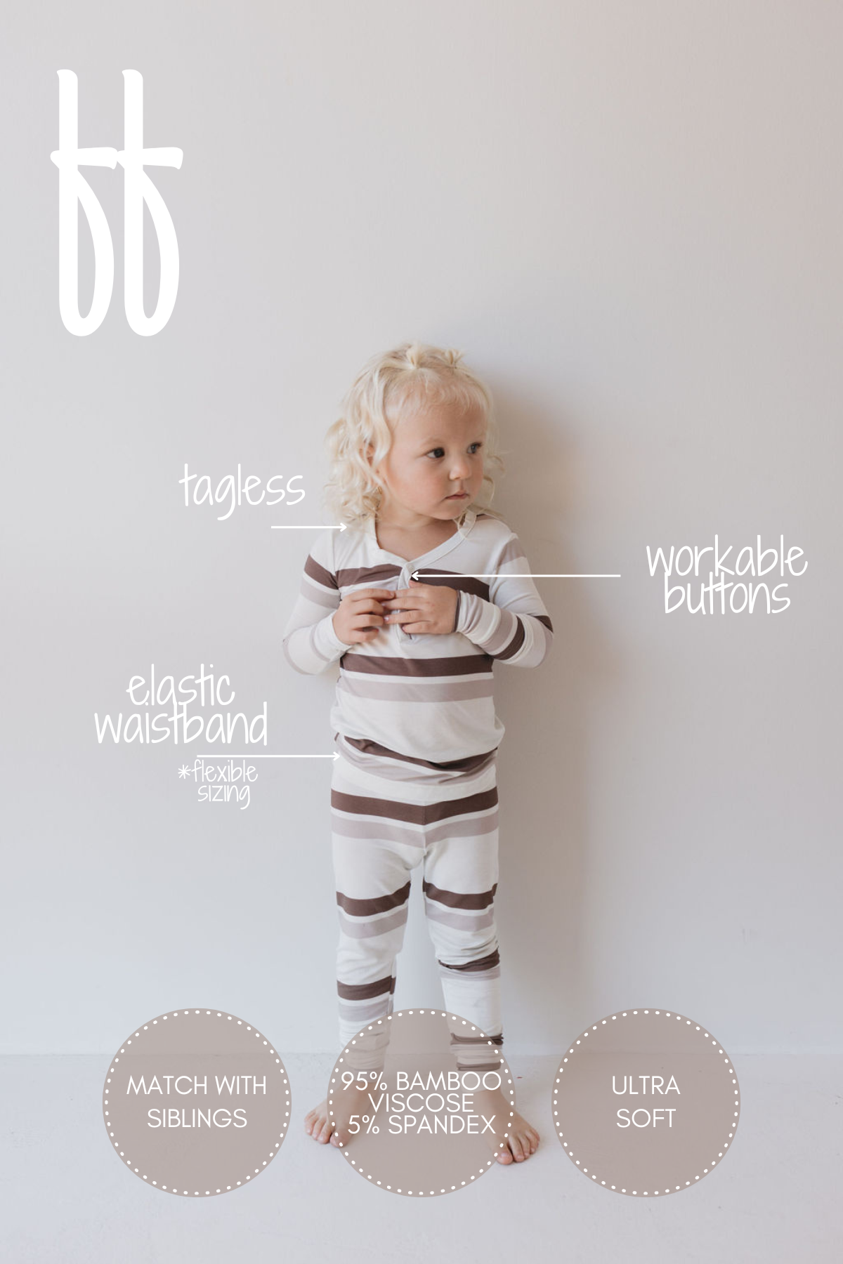 A young child with blond curly hair stands against a plain background wearing the Bamboo Two Piece Pajamas in Woodland Stripes by forever french baby. This striped set features workable buttons, an elastic waistband, and is crafted from breathable fabric made of 95% bamboo viscose and 5% spandex. The hypoallergenic pajamas are tagless and ultra-soft.