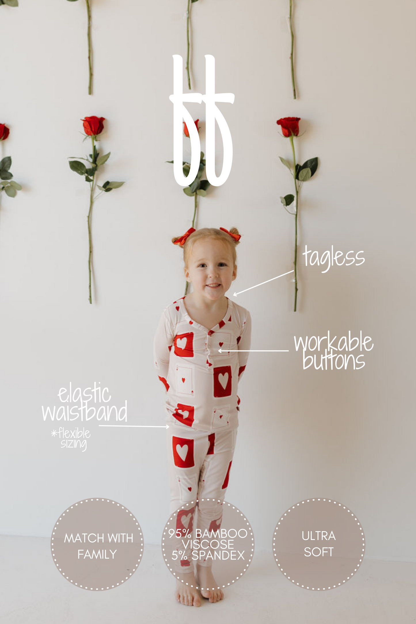 A child smiles wearing the "Love Day" bamboo pajamas by forever french baby, featuring white fabric with red hearts. Behind them are vertical rows of red roses. The pajamas are tagless with workable buttons, an elastic waistband, breathable 95% bamboo viscose, and ultra-soft material.