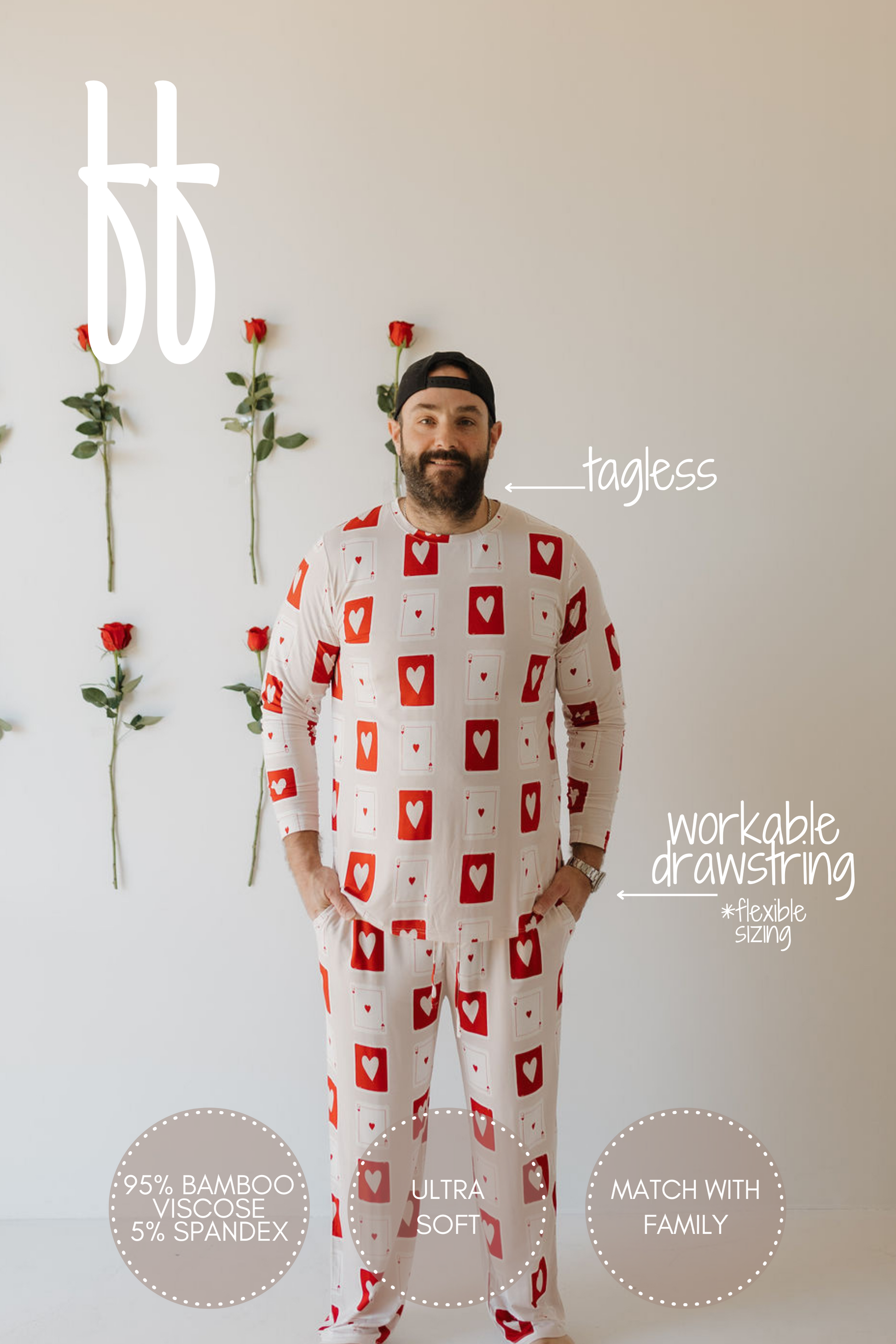 A person in forever french baby's "Love Day" heart-patterned men's bamboo pajamas stands by a rose-covered wall. The tagless, ultra-soft set is 95% bamboo viscose, 5% spandex, featuring breathable, hypo-allergenic fabric, a workable drawstring, and family matchability.