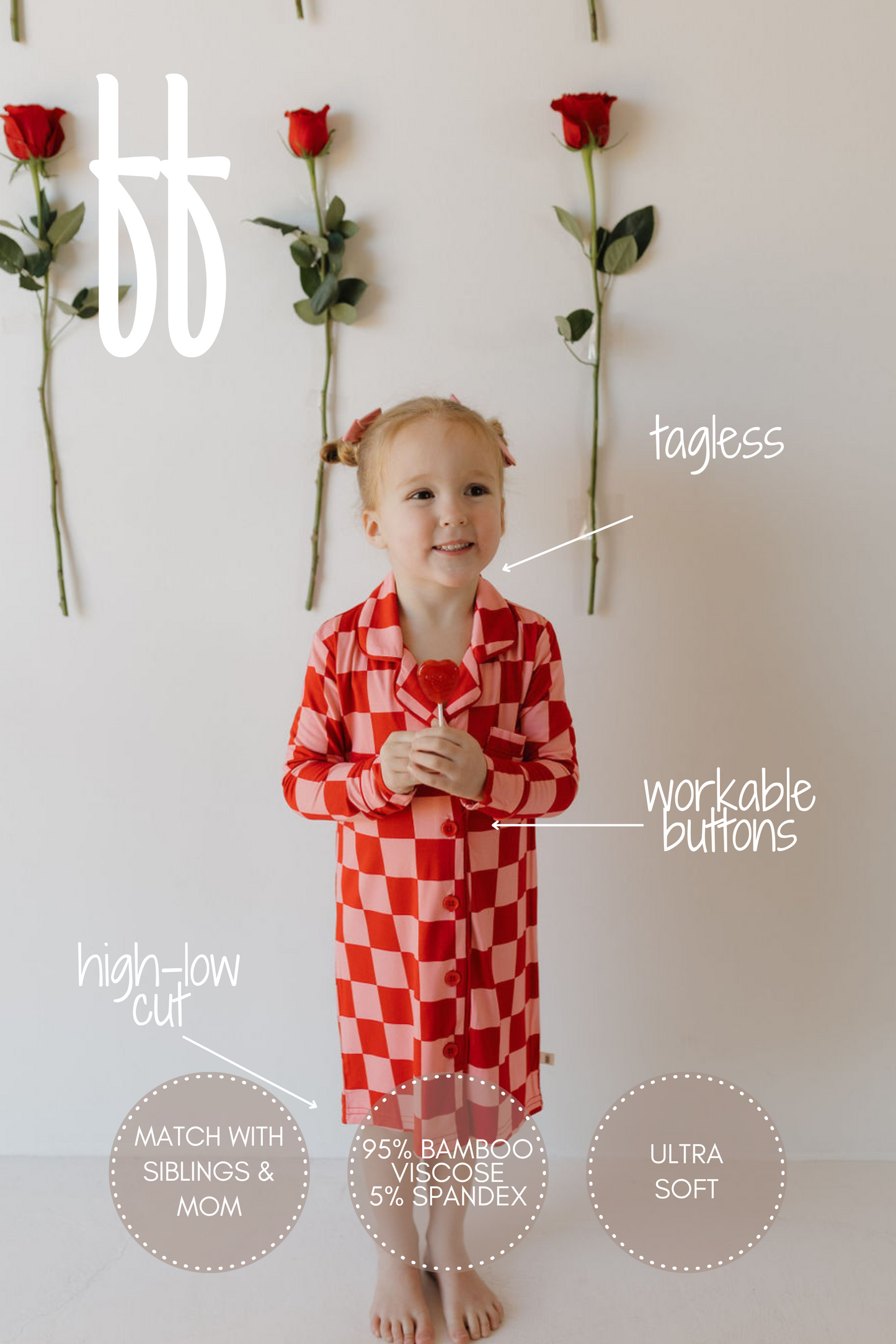 A young child with braided hair stands against a white wall, wearing the Toddler Bamboo Sleeping Dress by forever french baby. The red and white checkered dress features tagless design, workable buttons, and a high-low cut. Roses on the wall complement this hypoallergenic choice.