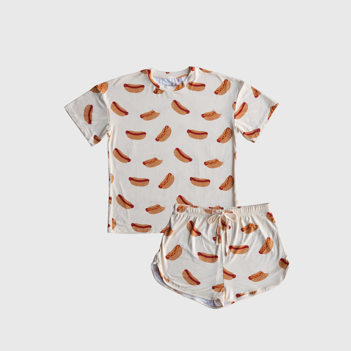 The Women's Bamboo Short Set | Hot Dogs by forever french baby features a playful hot dog print on a white background with a short-sleeve shirt and shorts. Made from breathable bamboo for extra comfort.