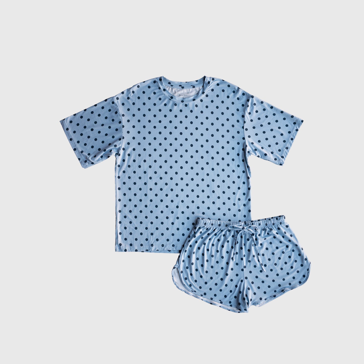 The Women's Bamboo Short Set | Sully by forever french baby, displayed on a plain white background, features a light blue short-sleeve shirt and shorts adorned with small black polka dots. Made from hypo-allergenic bamboo, this stylish set ensures comfort for a restful night's sleep.