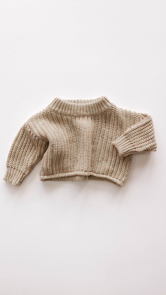 The Knit Sweater in Wheat Confetti by forever french baby is laid flat against a white background. Featuring a cozy turtleneck and long sleeves, its chunky knit pattern lends a warm, timeless charm, making it an essential piece for any baby wardrobe.